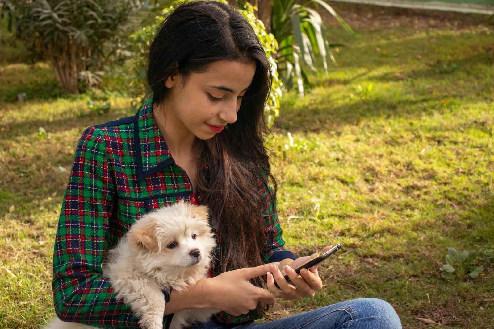 Dueña con el teléfono y su cachorro blanco